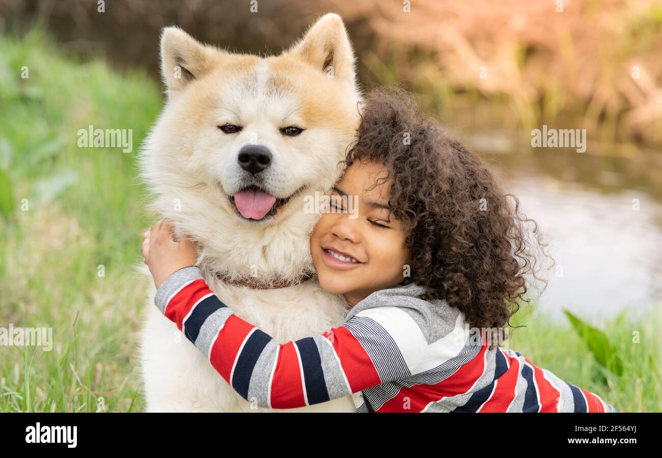 Lächelnder Junge umarmt Hund in der Natur Stockfoto