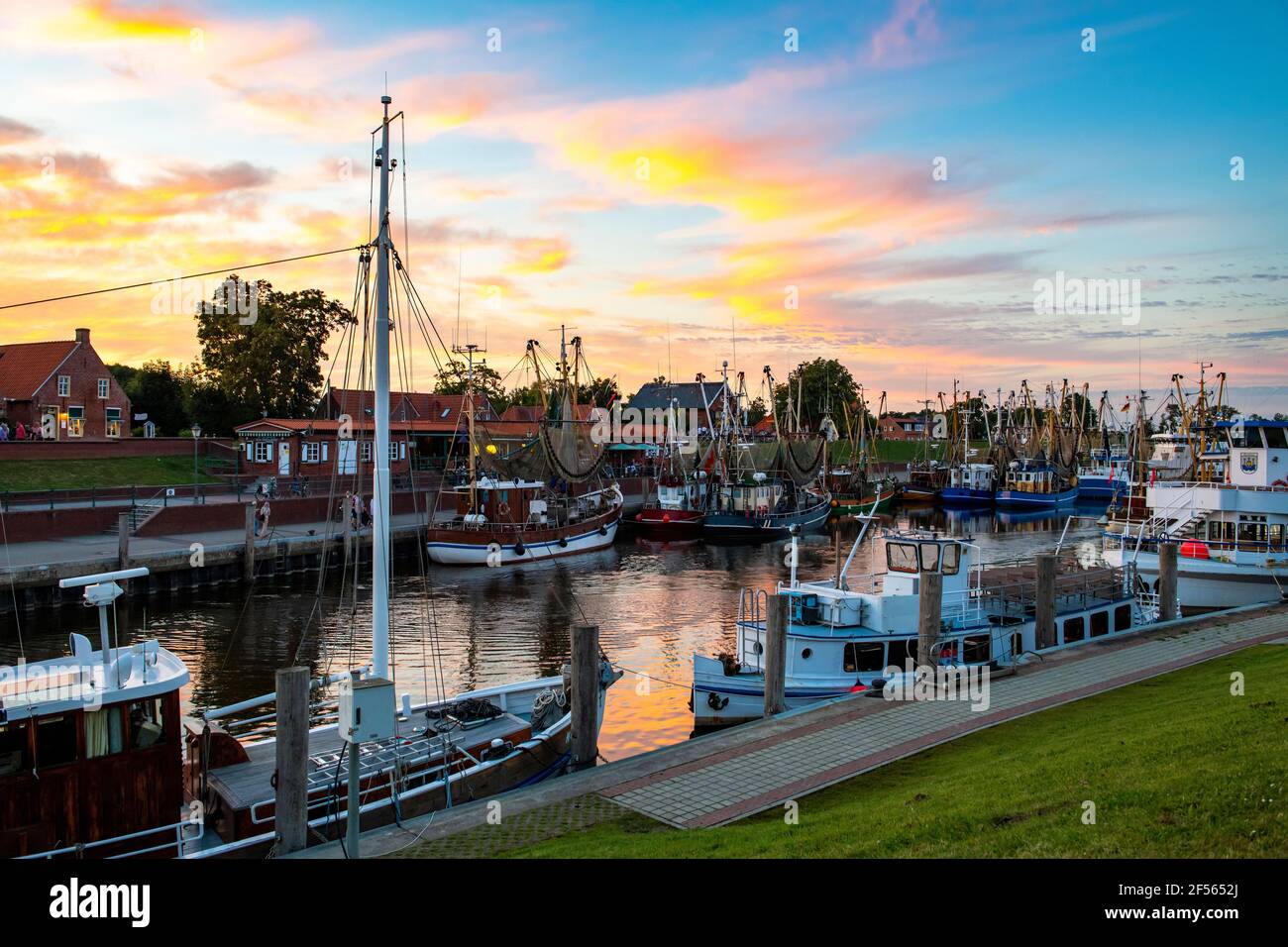 Deutschland, Niedersachsen, Greetsiel, Fischerboote liegen am Stadthafen bei launischer Dämmerung Stockfoto