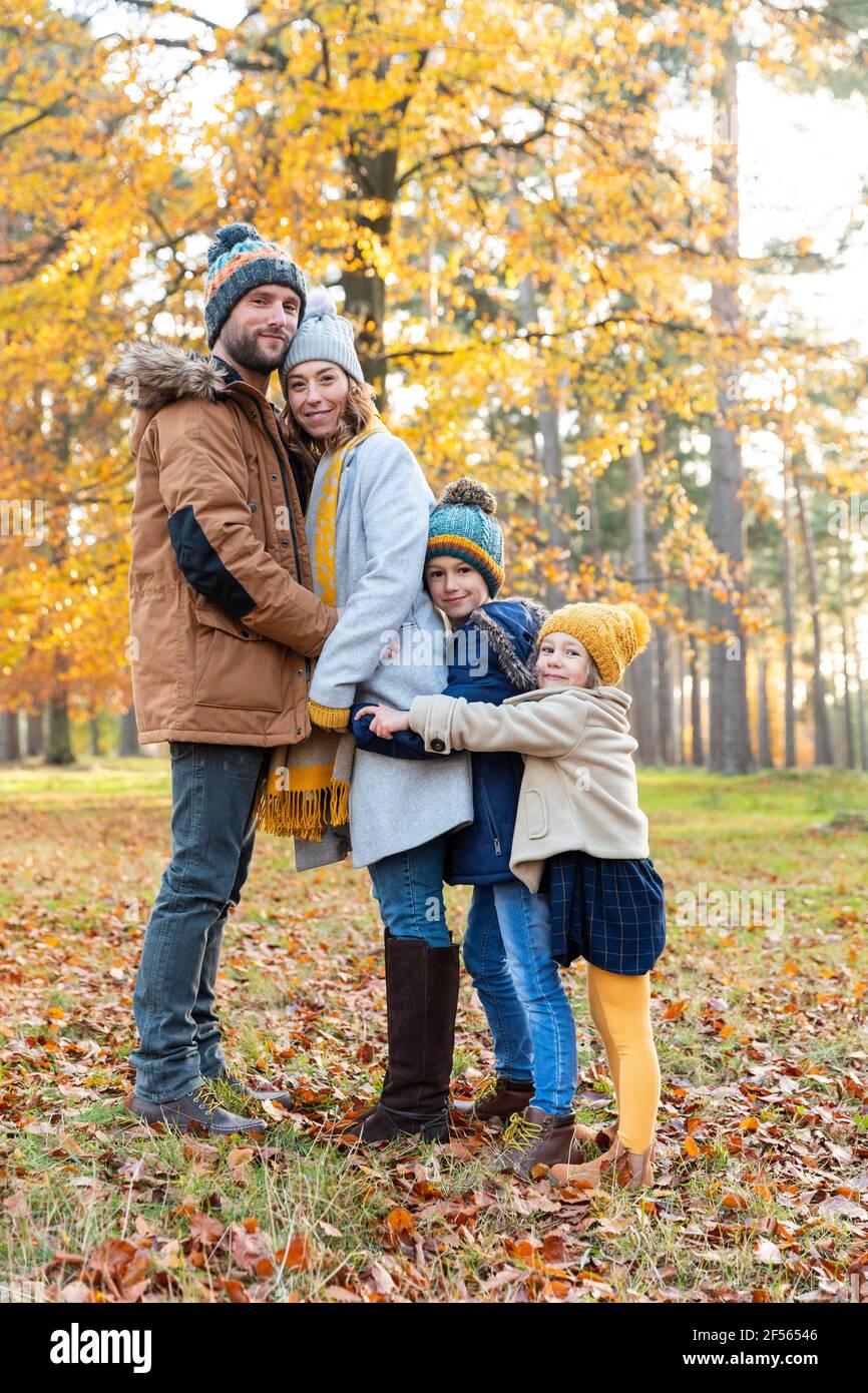 Familie umarmt sich gegenseitig, während sie im Herbst im Wald steht Stockfoto
