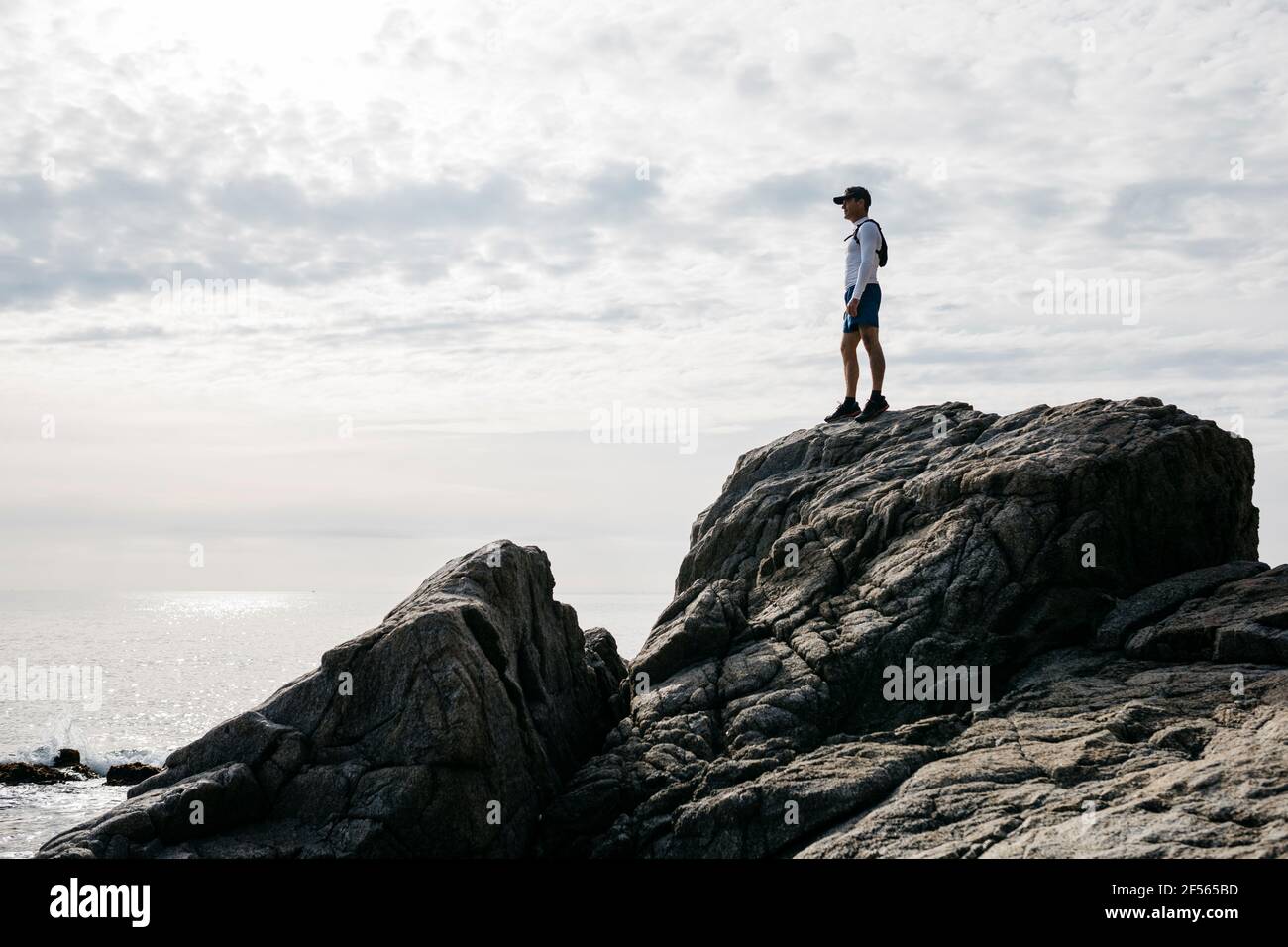 Mann steht auf Felsformation gegen bewölkten Himmel Stockfoto
