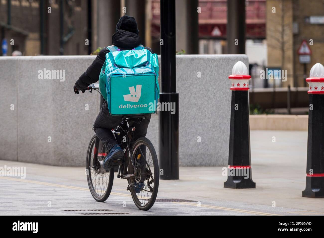 London, Großbritannien. 24. März 2021. Ein Deliveroo Rider fährt durch die City of London. Die Lebensmittelfirma bereitet sich auf eine Börsennotierung £8,8bn am 7. April vor, aber einige Kommentatoren haben auf das Investitionsrisiko hingewiesen, dass Lieferfahrer nicht als Angestellte eingestuft werden, also nicht die Rechte auf Mindestlohn, Urlaub oder Krankenstand haben. Die meisten Fahrer des Unternehmens wird mit Boni bis zu £10.000 nach dem Börsengang vergeben werden. Kredit: Stephen Chung / Alamy Live Nachrichten Stockfoto