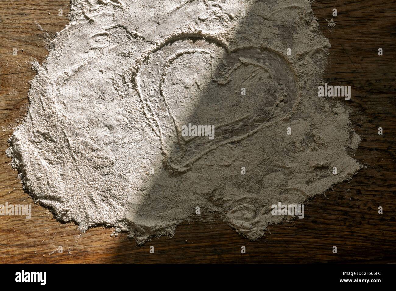 Zum Teil schattengespalten Herz durch Finger in Mehl beim Schneiden gezogen Platine Stockfoto