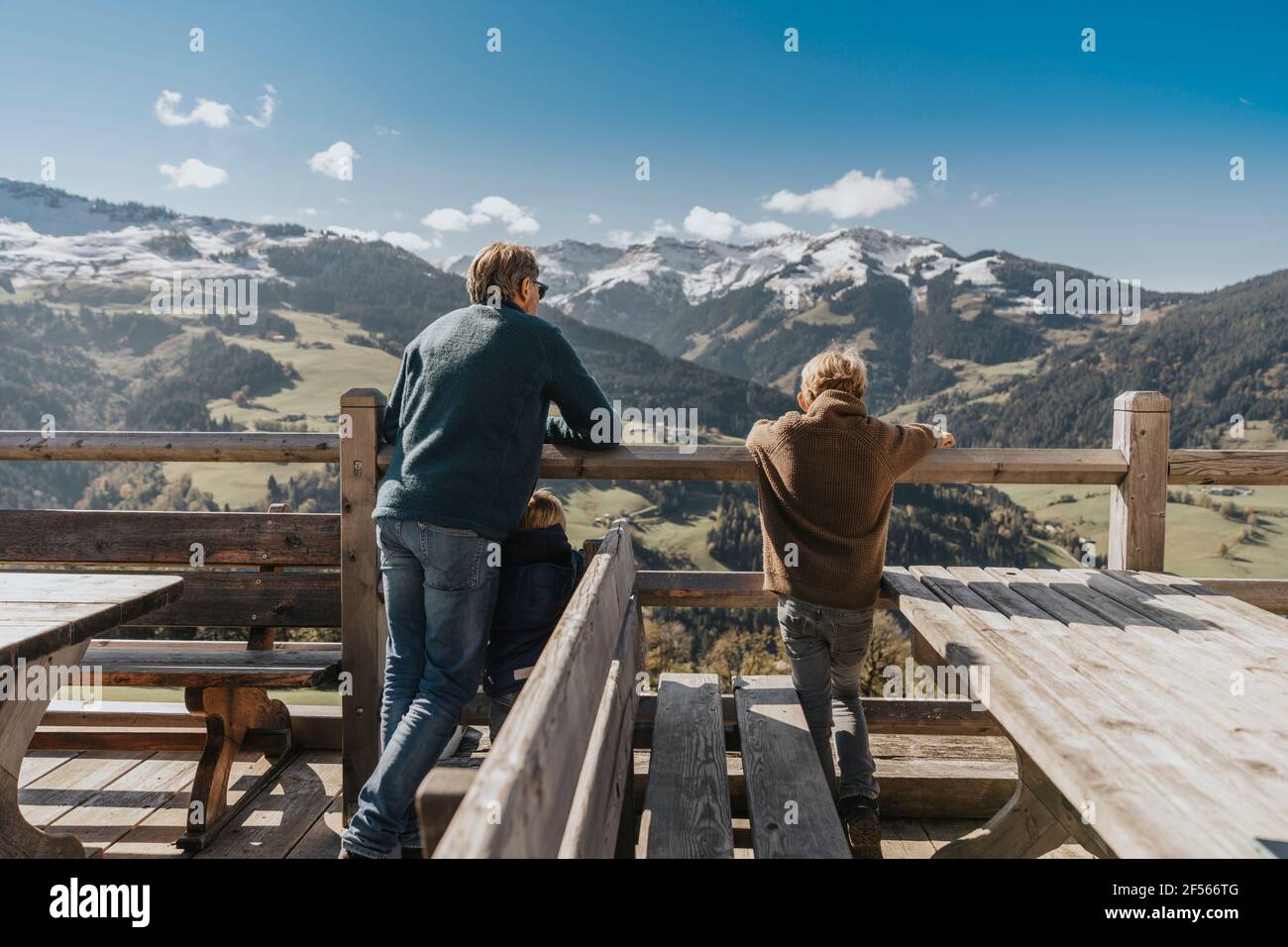 Vater mit zwei Kindern, die am Geländer gelehnt sind, während sie die Leoganger Berge im Salzburger Land betrachten Stockfoto