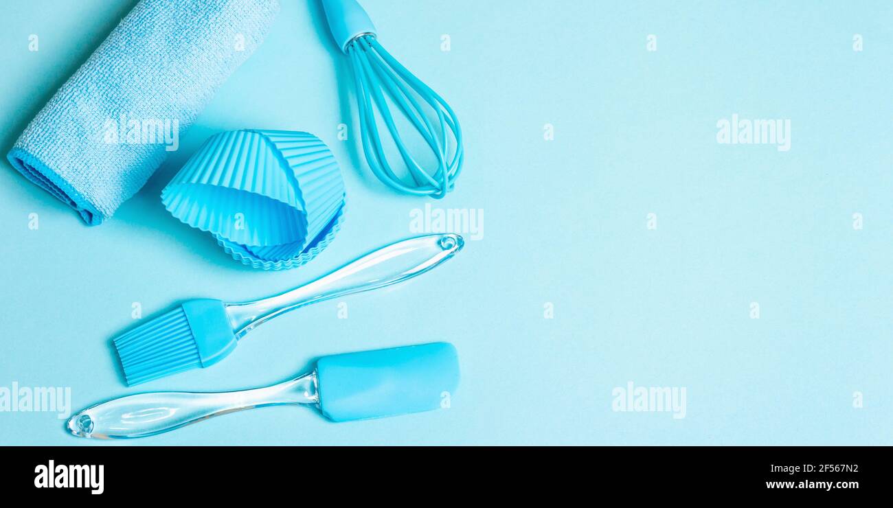 Backkonzept isoliert auf pastellblauem Hintergrund. Ein Set aus Spachtel, Schneebesen, Pinsel, Muffin Dosen und Serviette. Alle Objekte werden in der gleichen Farbe en abgeglichen Stockfoto