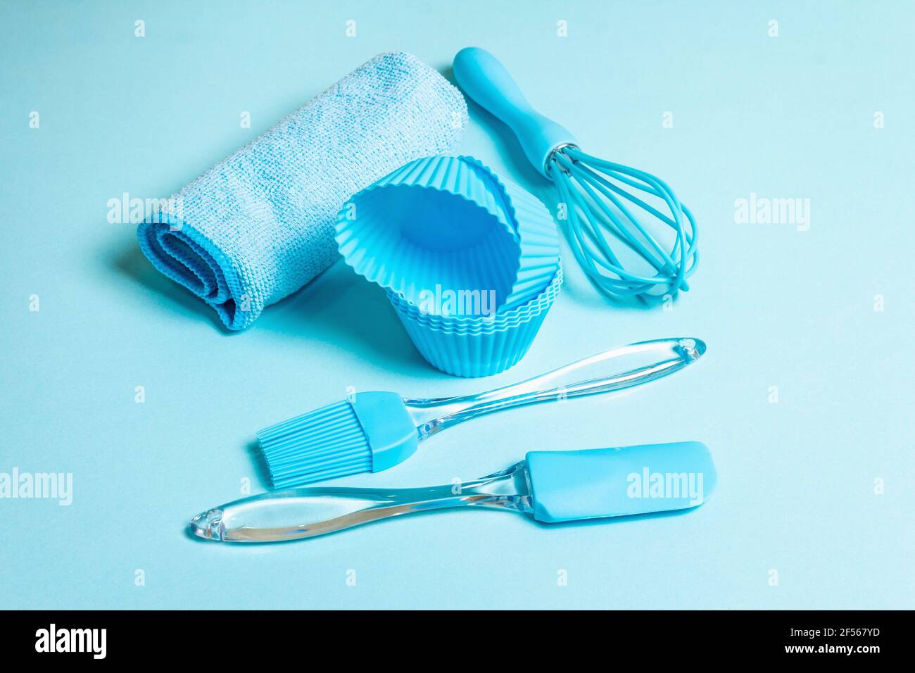 Backkonzept isoliert auf pastellblauem Hintergrund. Ein Set aus Spachtel, Schneebesen, Pinsel, Muffin Dosen und Serviette. Alle Objekte werden in der gleichen Farbe en abgeglichen Stockfoto