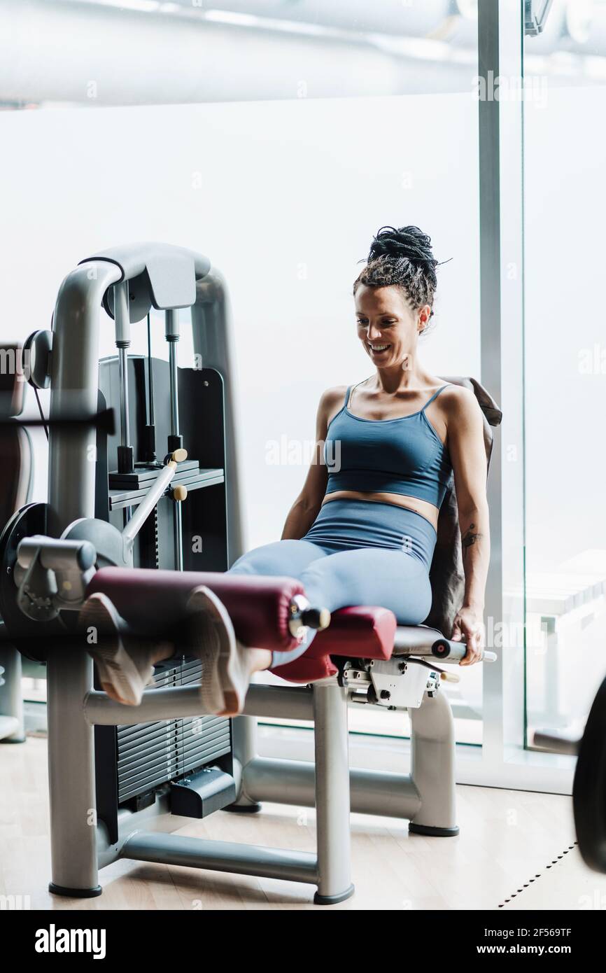 Lächelnde Sportlerin beim Training auf einem Kraftgerät im Fitnessstudio Stockfoto