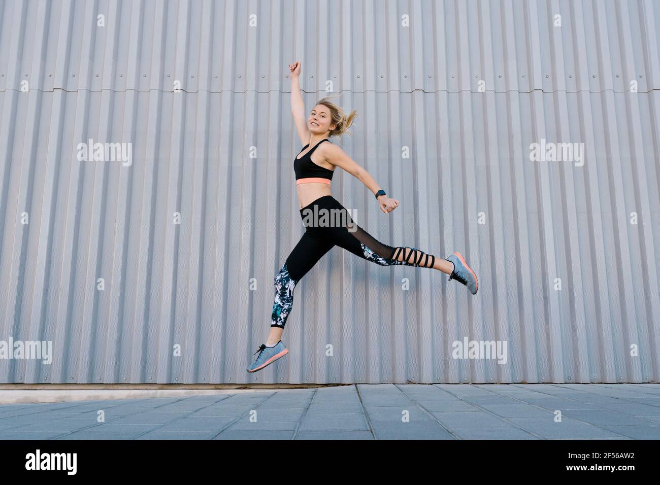 Unbeschwerte weibliche Sportlerin, die beim Sporttraining an der Wand springt Stockfoto