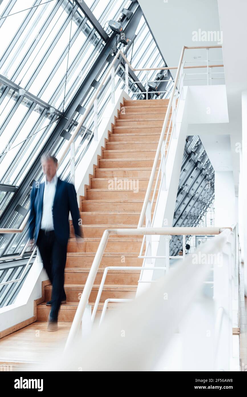 Geschäftsmann, der von der Treppe im Büroflur nach unten geht Stockfoto