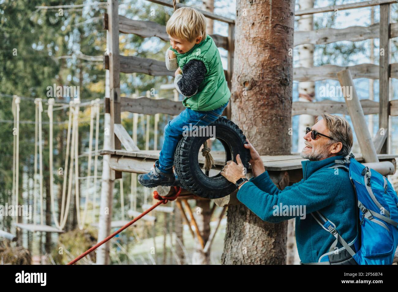 Glücklicher Vater mit Sohn beim Seilparcours im Wald im Salzburger Land, Österreich Stockfoto