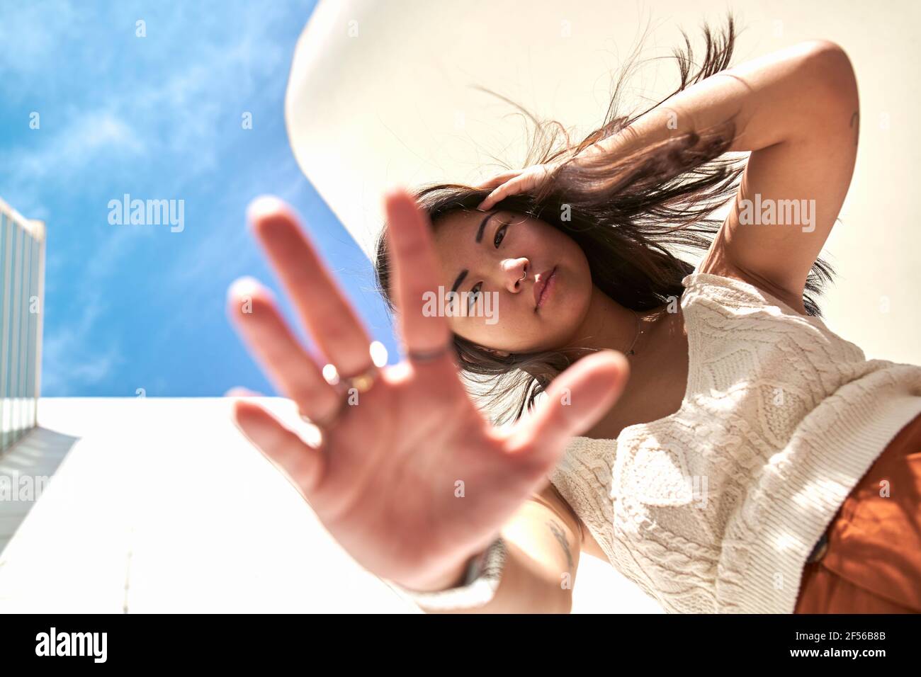 Junge Frau mit der Hand im Haar und Stop-Geste Sonniger Tag Stockfoto