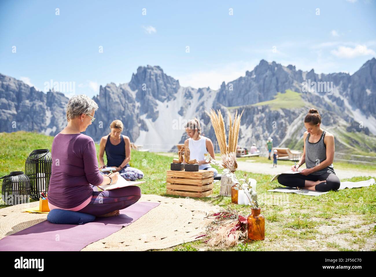Kaukasische Frauen schreiben auf Buch, während sie am Himmel sitzen Sonniger Tag Stockfoto