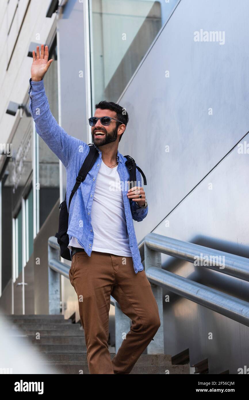 Fröhlicher Geschäftsmann winkt, während er sich auf der Treppe nach unten bewegt Stockfoto