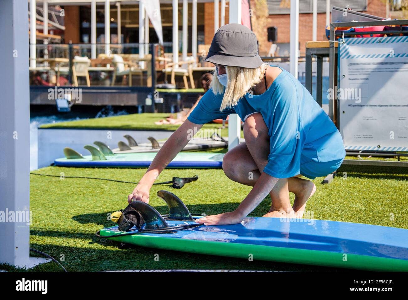 Arbeiterin, die während des COVID-19 die Schwanzflosse am Surfbrett justiert Stockfoto