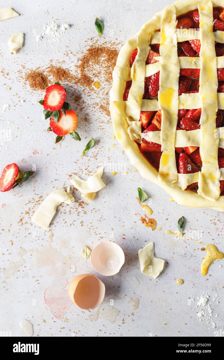 Hände des Mannes, der Eierwäsche auf den rohen Erdbeerkuchen anwendet Stockfoto