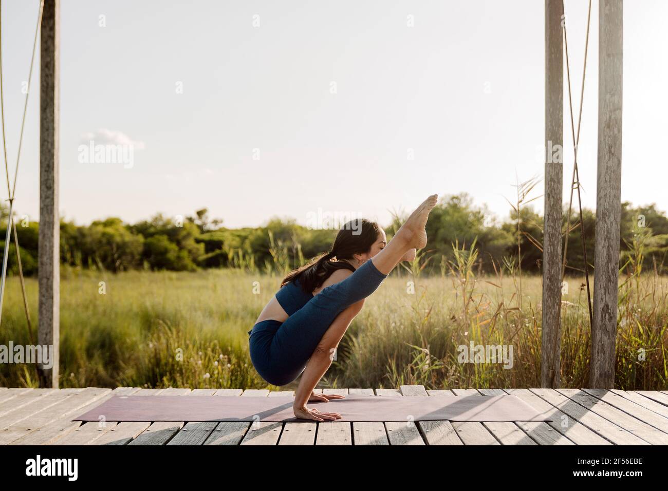 Starke Frau, die Tittibhasana Yoga macht, posiert im Pavillon Stockfoto