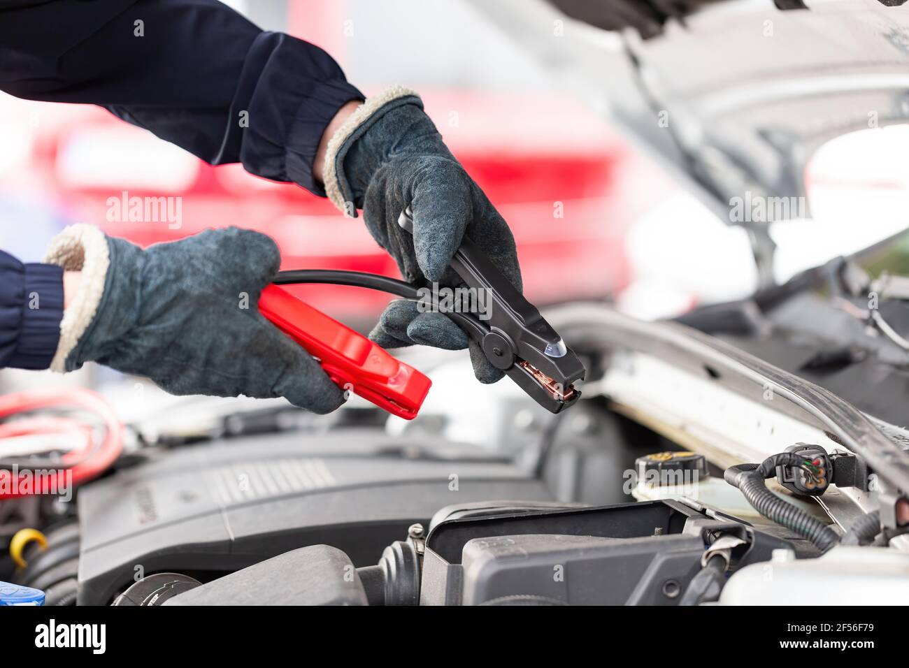 Der Mensch versucht, den Motor mit Überbrückungskabeln in der Nähe zu starten Nach oben Stockfoto