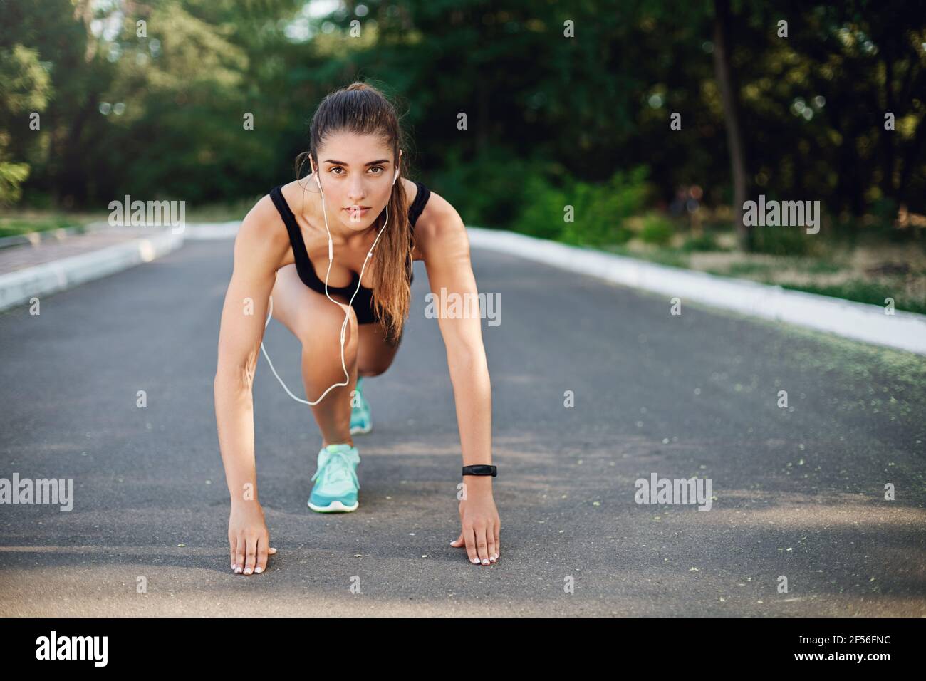 Sport, Fitness und urbanes Lifestyle-Konzept. Motivierte gut aussehende Frau führen ein aktives Leben, tun Morgenlauf, Sprinter stehen niedrigen Start auf Beton Stockfoto