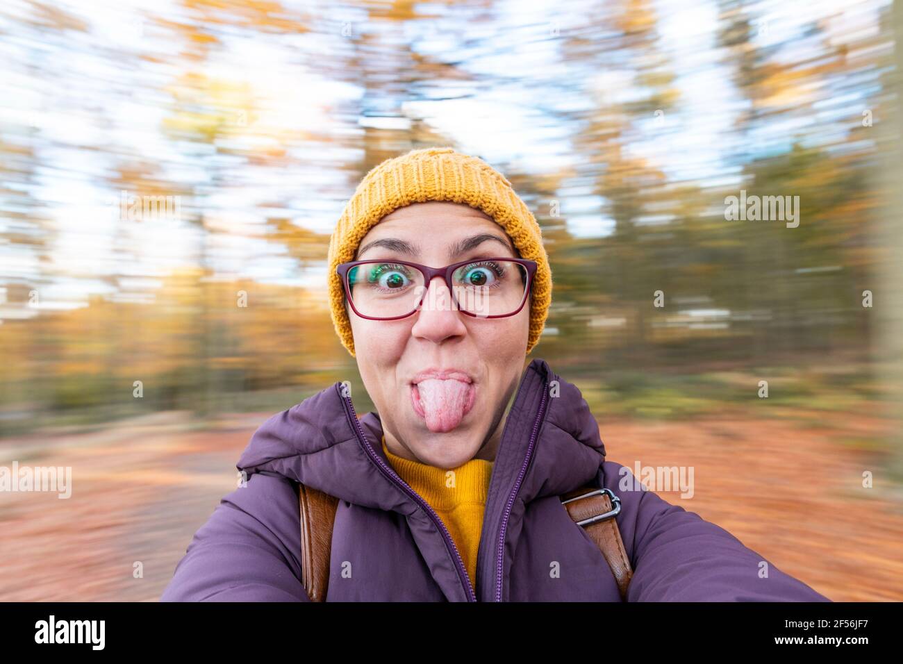 Sorglose Frau, die im Wald vor verschwommenem Hintergrund die Zunge herausstreckt Stockfoto