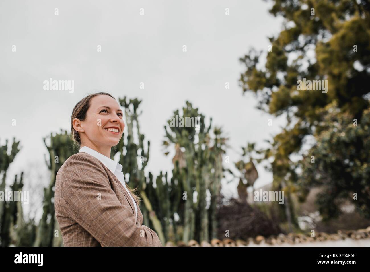 Lächelnde Geschäftsfrau mit gekreuzten Armen, die wegschauen Stockfoto