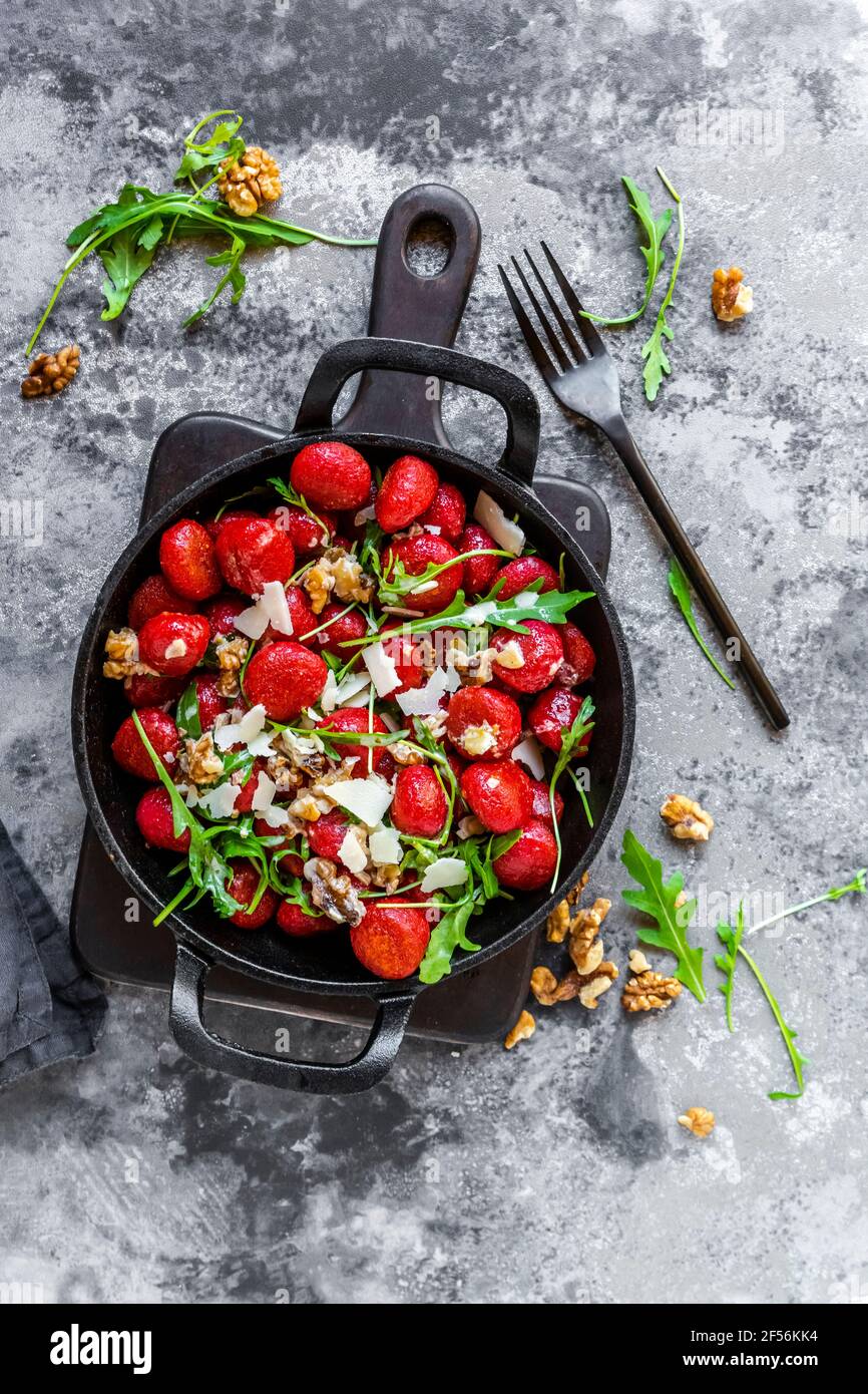 Rote Beete Gnocchi in cremiger Walnusssauce, Rucola und Parmesan in Pfanne Stockfoto