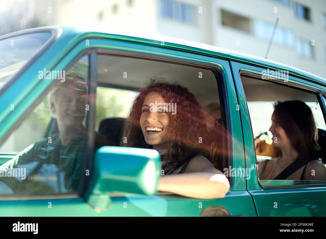 Lächelnde Frau schaut weg, während sie mit Freunden im Auto sitzt Stockfoto