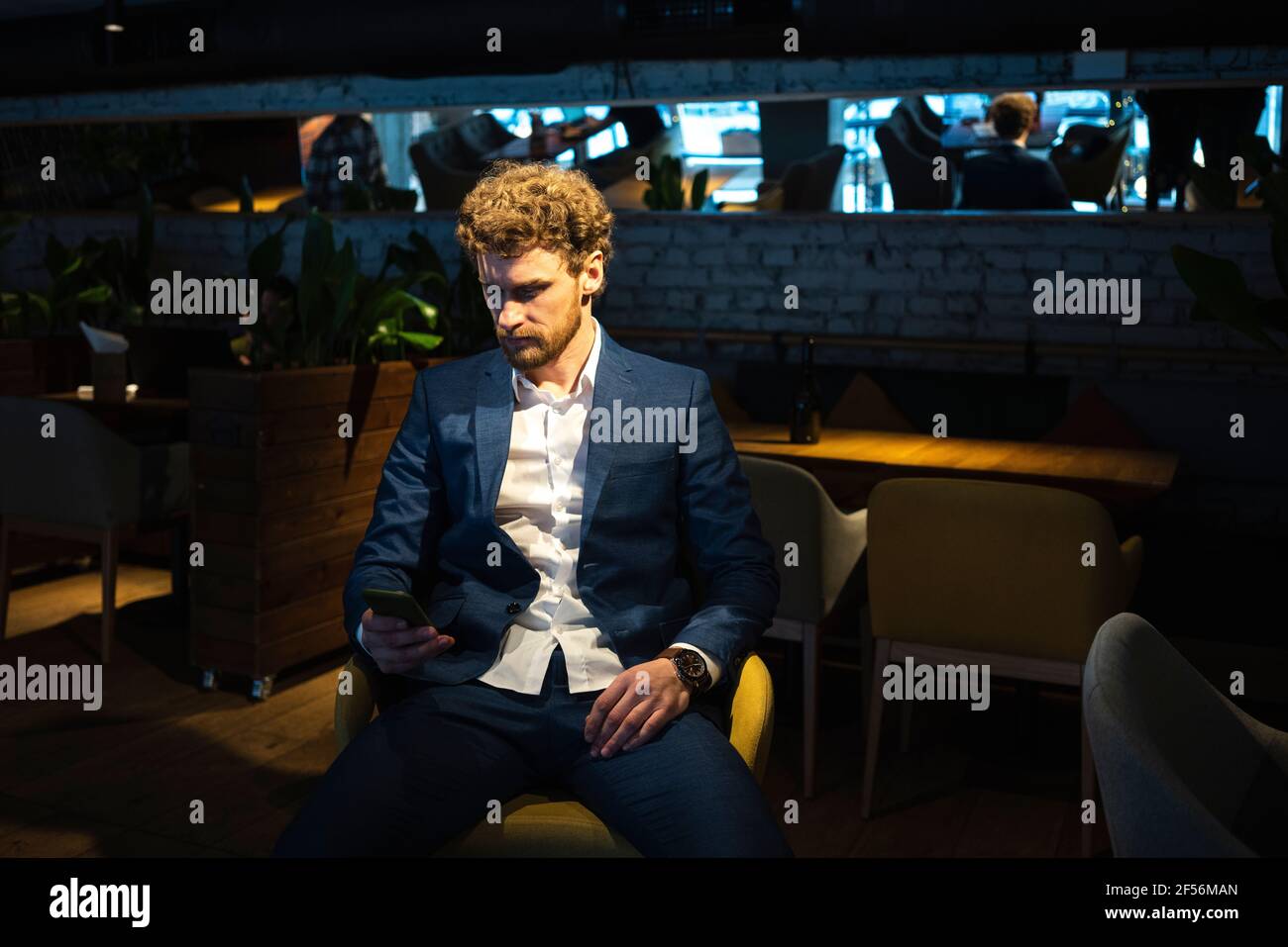 Männlicher Besitzer trägt Anzug mit Smartphone, während er sitzt Café Stockfoto