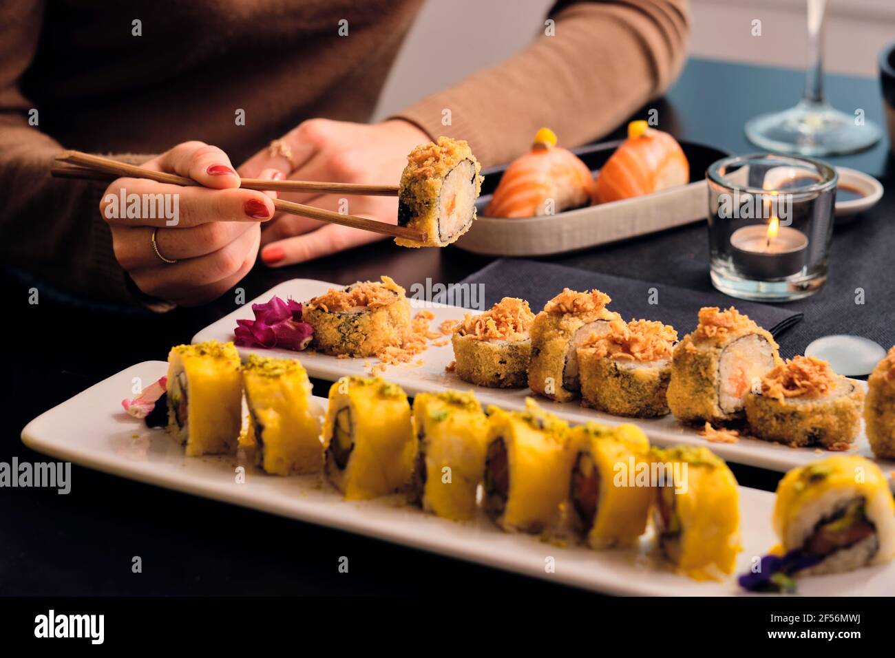 Junge Gäste essen Sushi mit Essstäbchen im Restaurant Stockfoto