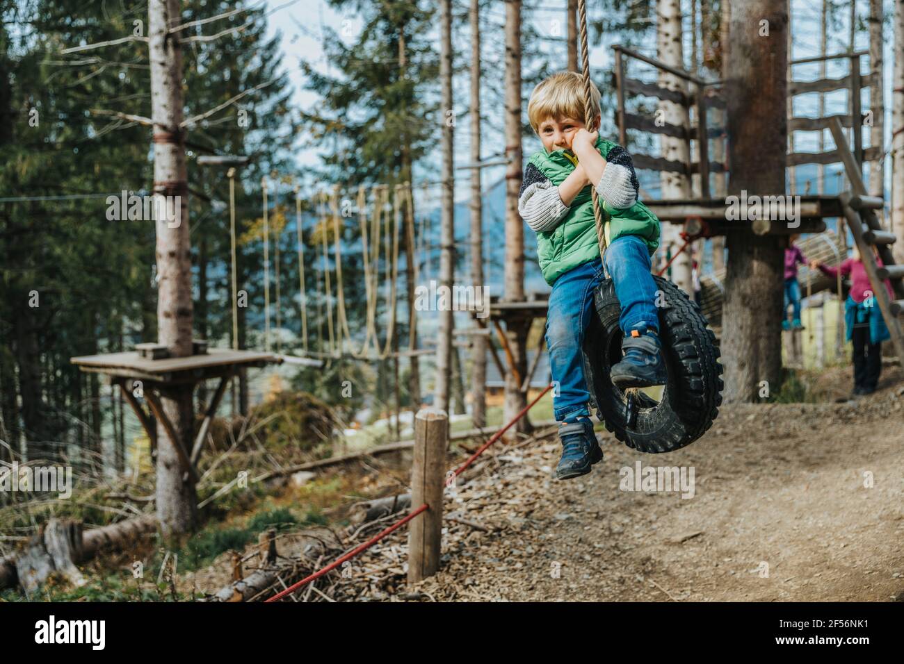 Junge schwingt mit Seil auf Reifen im Wald im Salzburger Land, Österreich Stockfoto