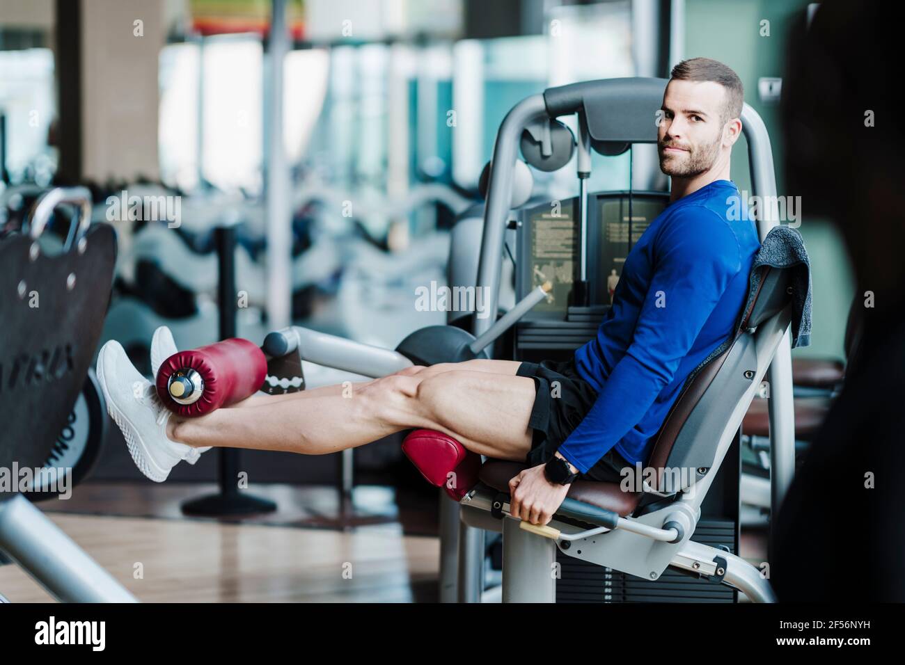 Ein gutaussehender Sportler, der im Fitnessstudio auf einem Gewichtheber trainiert Stockfoto