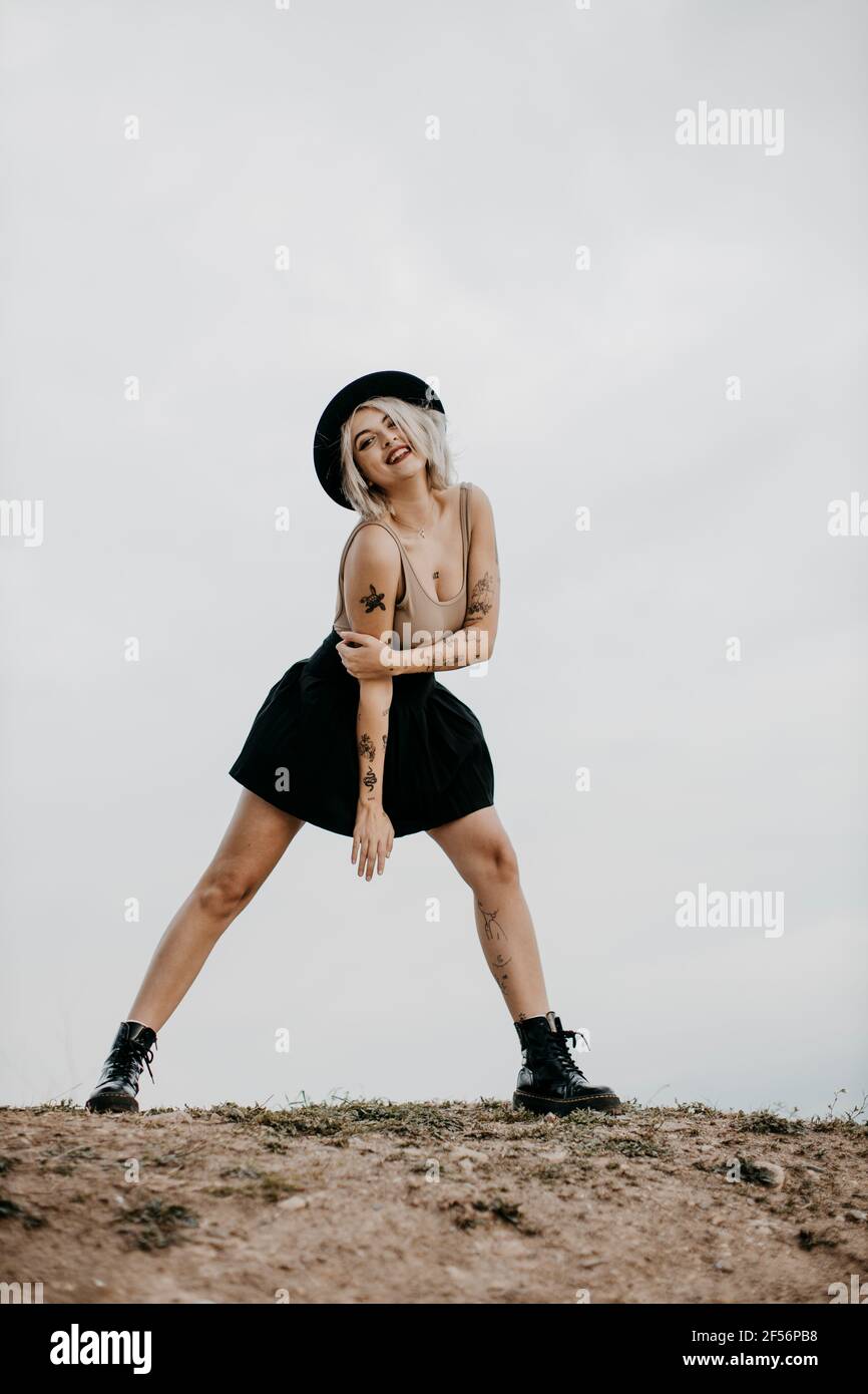 Junge Frau mit Hut, die auf einem Bein gegen den Himmel steht Stockfoto