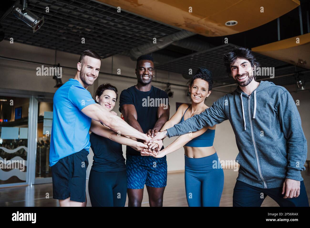Lächelnde, multiethnische Gruppe von Sportlern, die im Fitnessstudio huddeln Stockfoto
