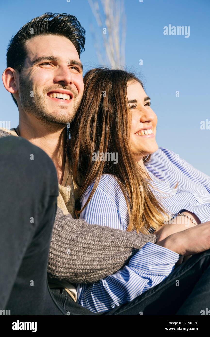 Fröhliche Frau, die mit dem Mann im Park sitzt Stockfoto