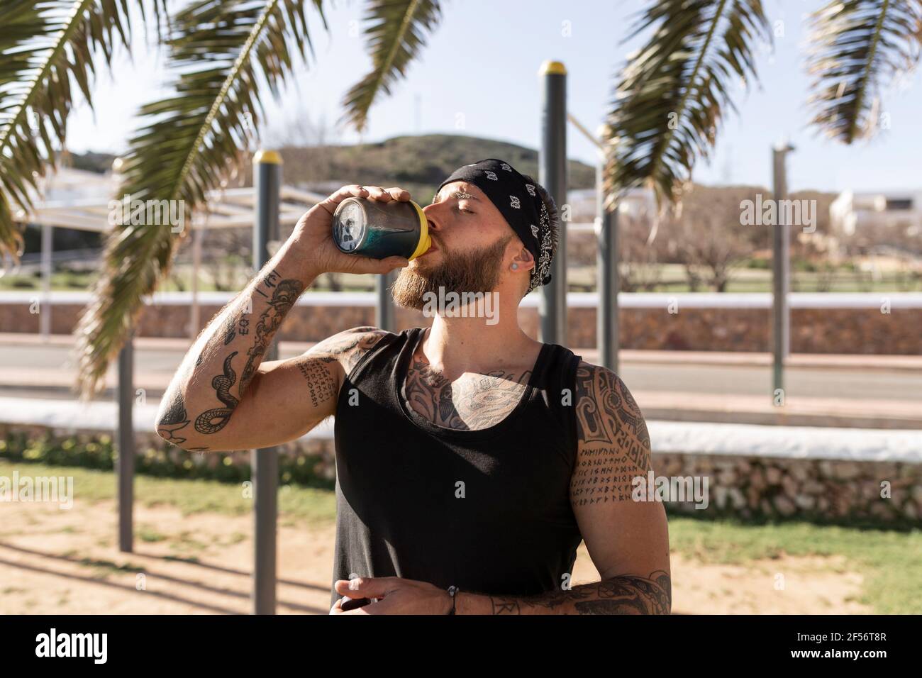 Durstiger männlicher Sportler, der Energiegetränk im Park auf sonnig hat Tag Stockfoto