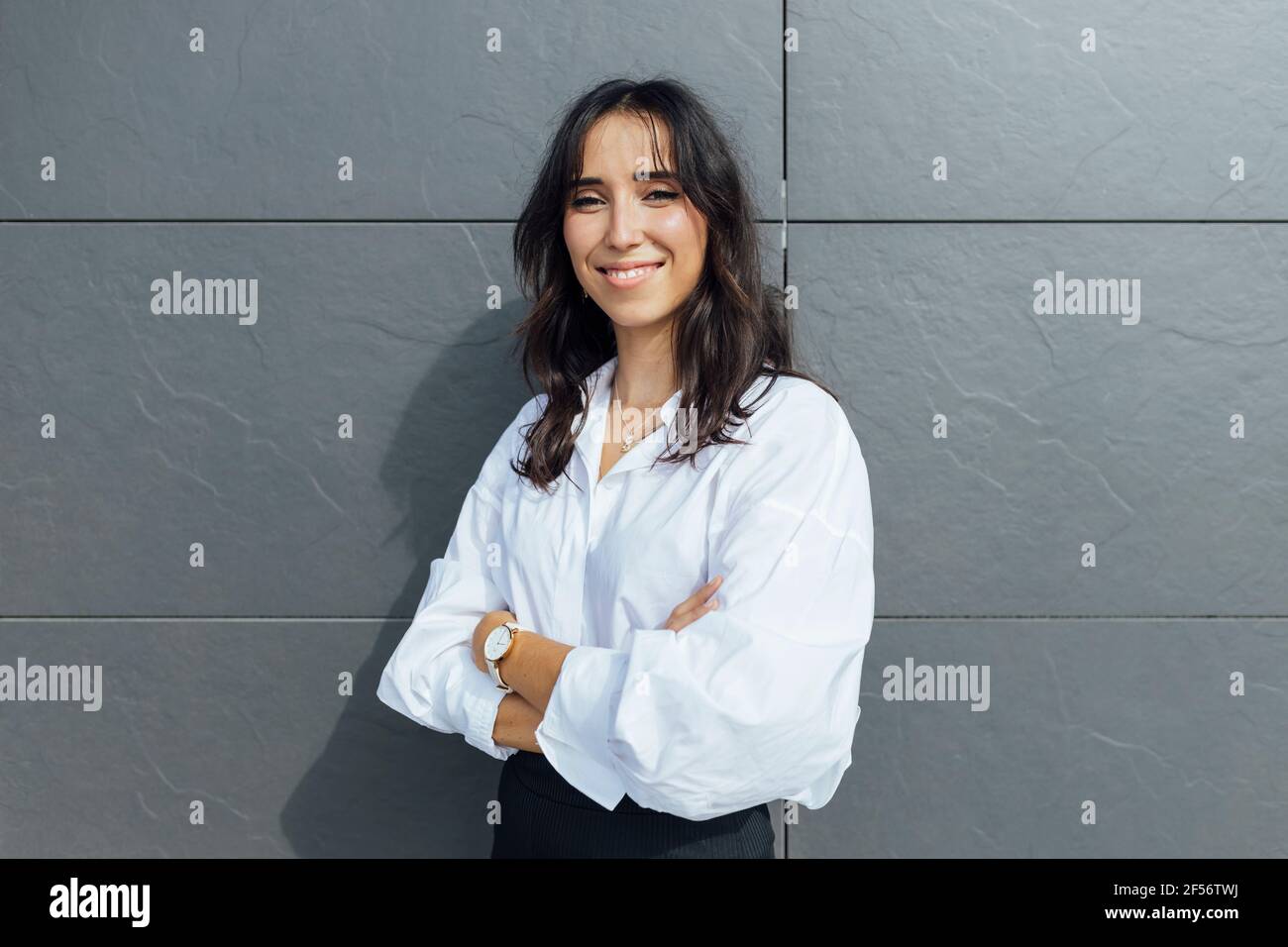 Unternehmerin mit einem Kreuz an der grauen Wand Stockfoto