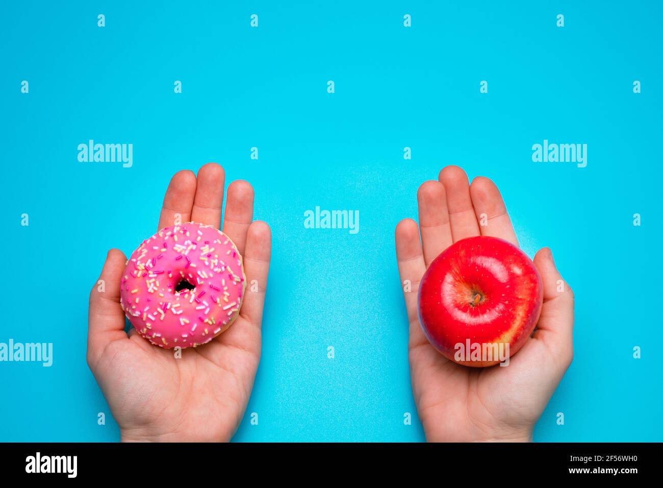 Frau, die einen Apfel und einen Donut in den Händen hält. Gesunde Lebensweise oder Ernährung Konzept. Stockfoto