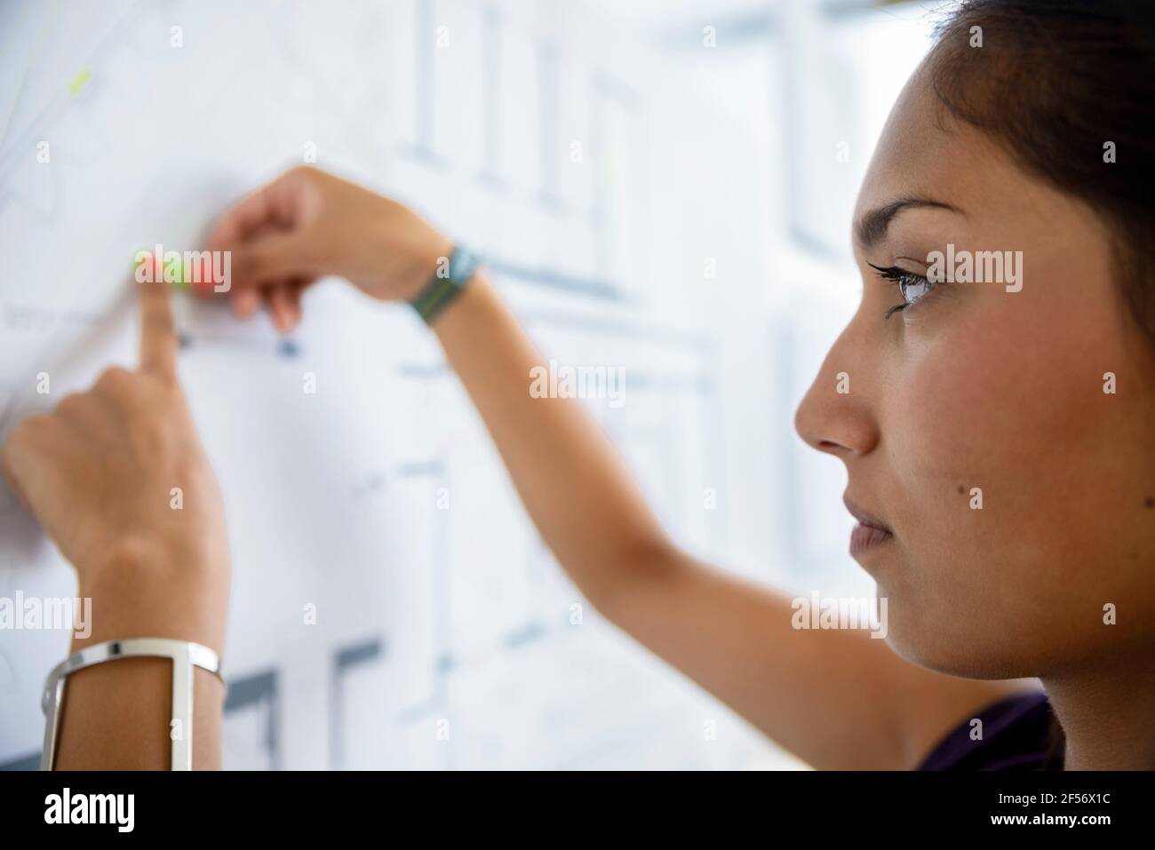 Fokussierte weibliche Architektin, die mit Graphen auf Whiteboard in arbeitet Büro Stockfoto