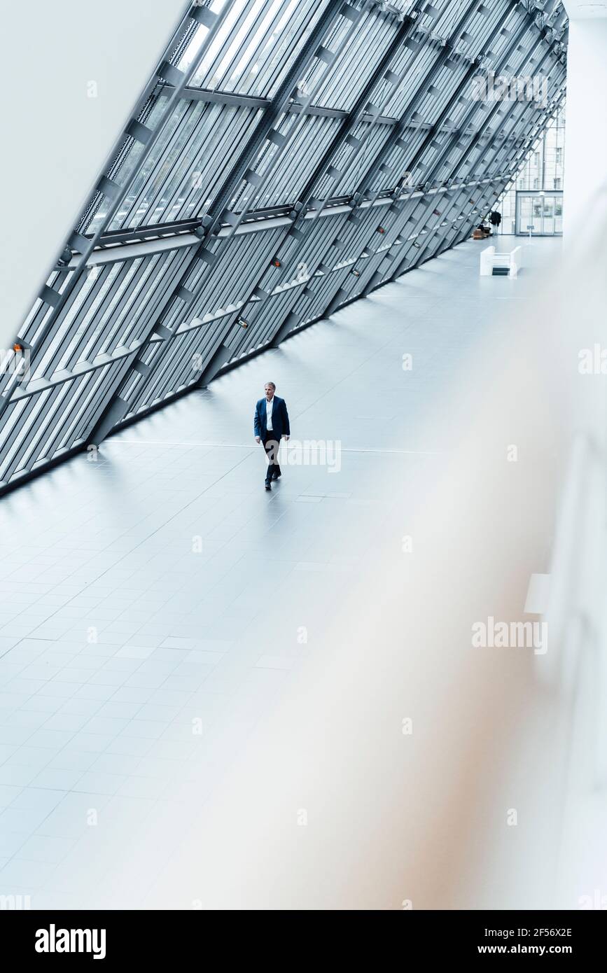 Leitender männlicher Geschäftsmann, der im Büroflur läuft Stockfoto