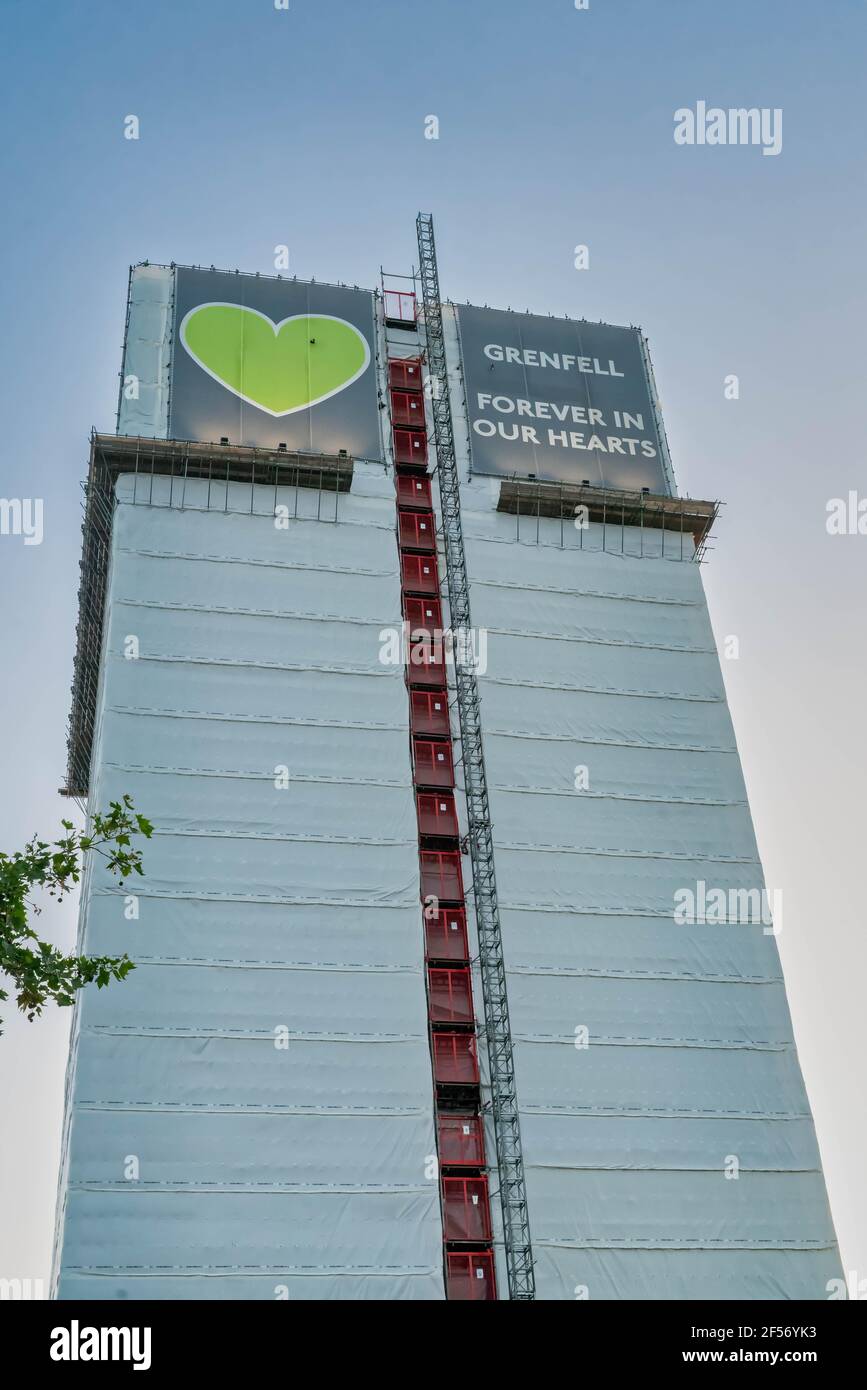 Der Grenfell-Turm, der mit einer weißen Plane bedeckt ist, mit dem grünen Herzlogo und der Aufschrift oben, steht hoch am blauen Himmel. Stockfoto