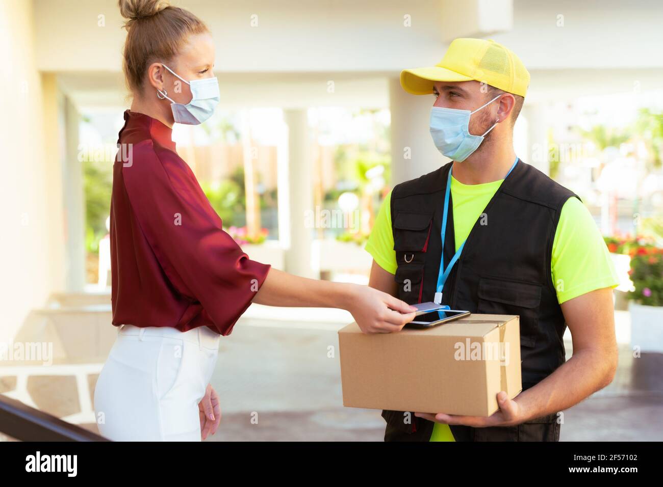 Lieferung von Waren und Paketen an Kunden durch den Schutz mit medizinischen Masken. Online-Bestellung unter Quarantäne Coronavirus covid-19. Stockfoto