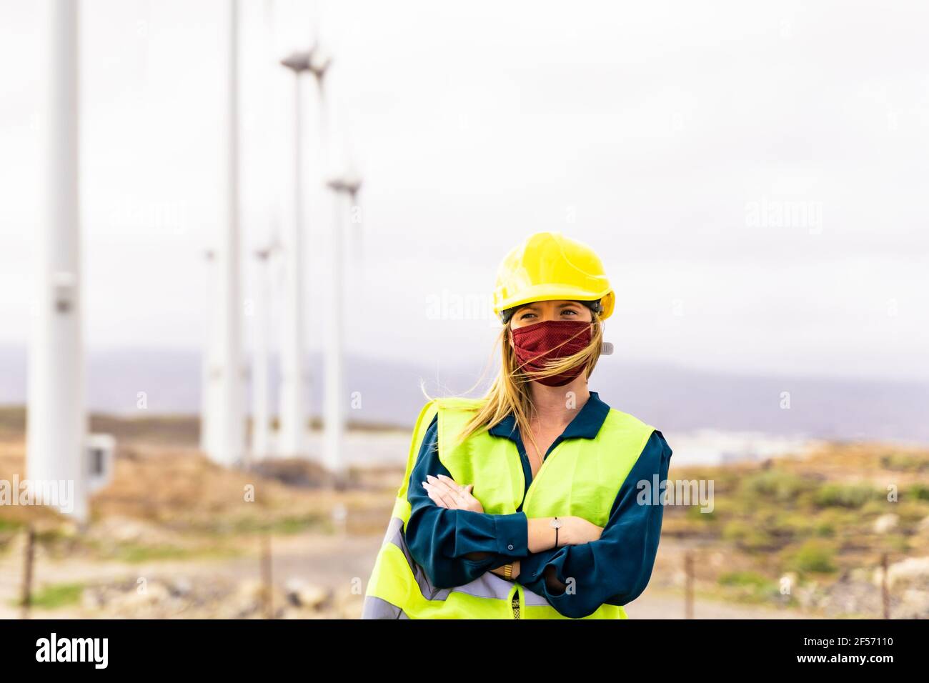 Vorderansicht einer jungen Ingenieurin, die in einem Windturbinenpark arbeitet. Saubere Energie, erneuerbare Energie und Umweltkonzept. Stockfoto