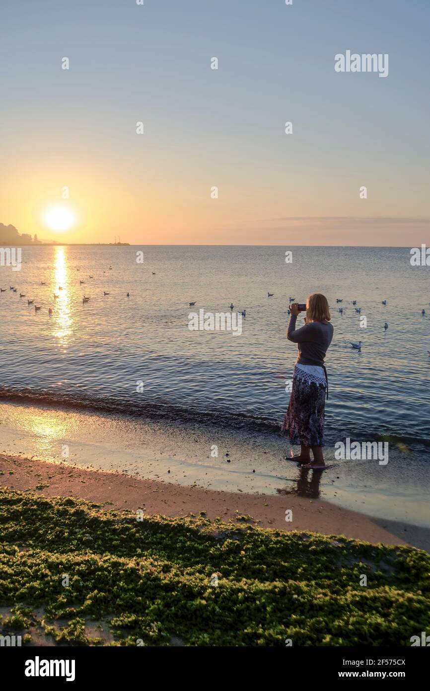 Frau begrüßt den Sonnenaufgang, Schwarzes Meer, Bulgarien, Stockfoto