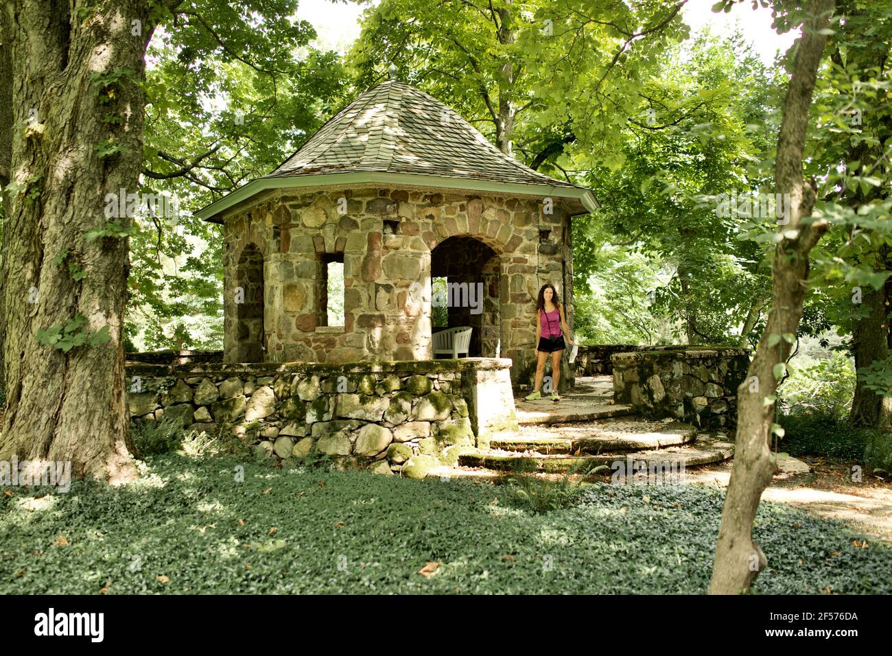 Frau, die vor einem Steingebäude im Garten von Greenwood Gardens in Short Hills, NJ, steht Stockfoto