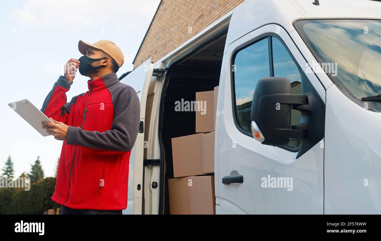 Delivery Mann Mitarbeiter mit Gesichtsmaske Lieferung Paket. Hochwertige Fotos Stockfoto