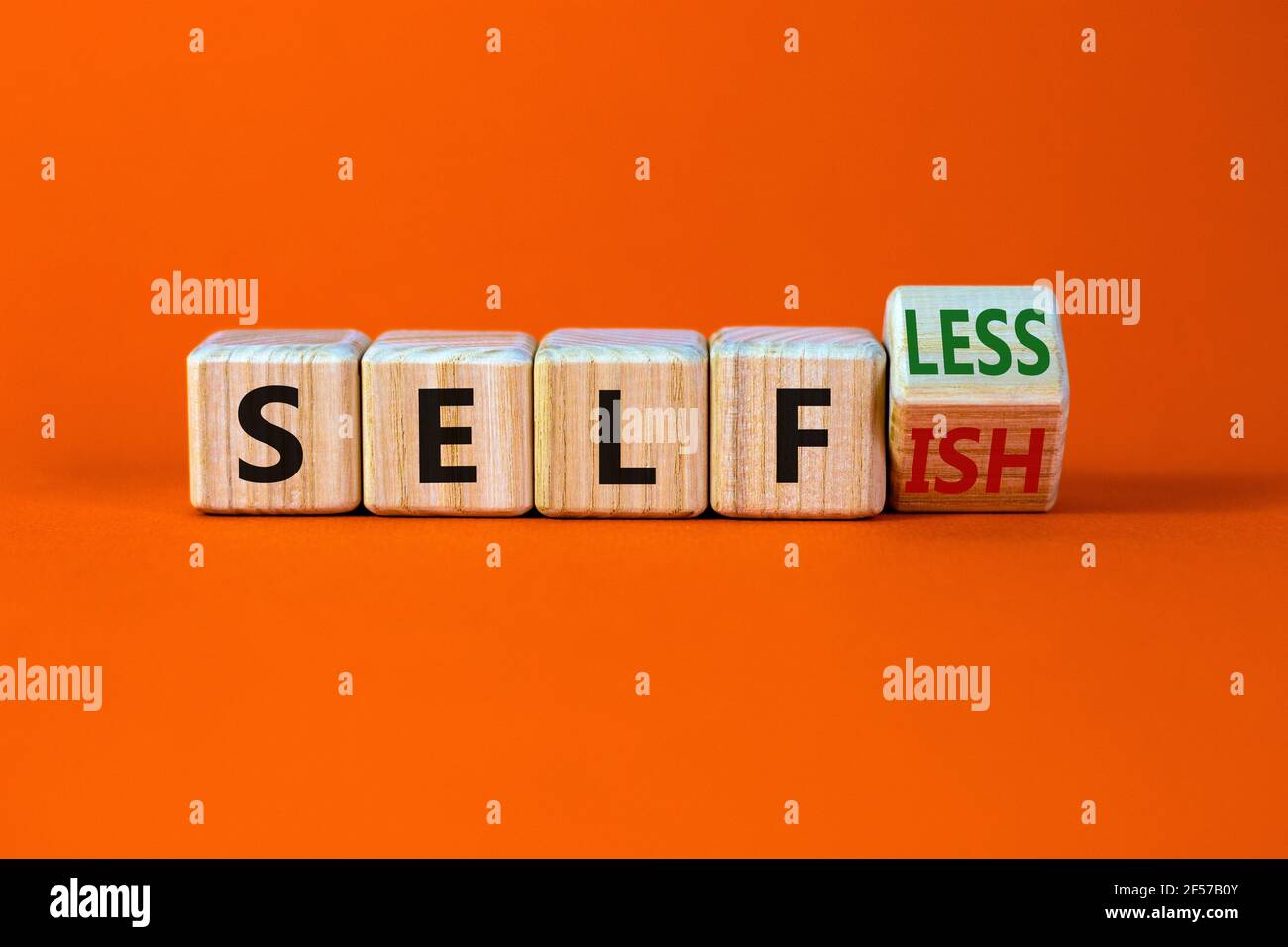 Selbstsüchtiges oder selbstloses Symbol. Drehte Würfel und änderte das Wort 'Selfish' zu 'Selfless'. Schöner orangefarbener Hintergrund, Kopierbereich. Business, psuchologica Stockfoto
