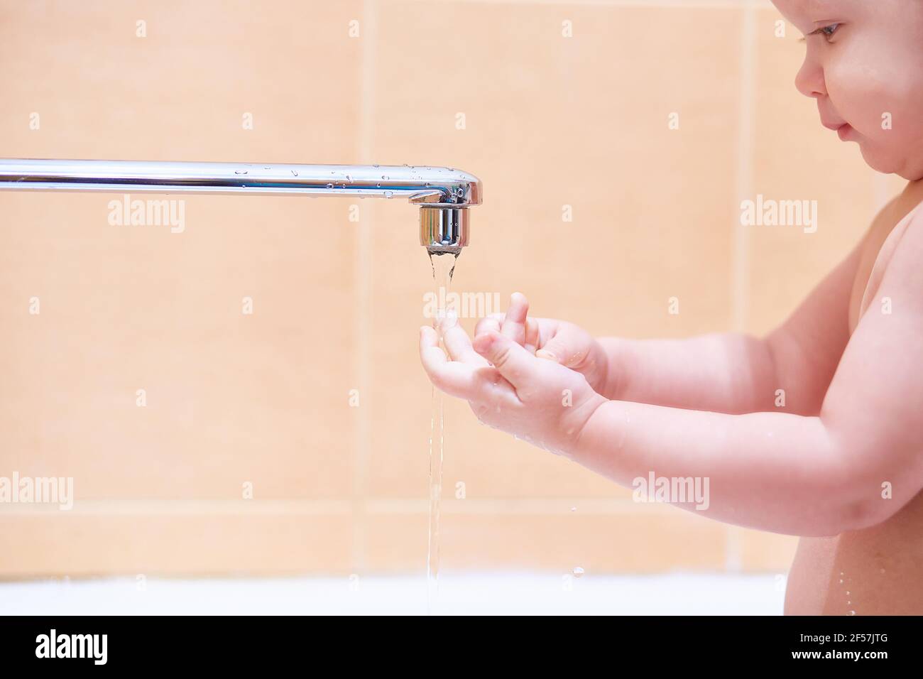 Kleinkind wäscht unter fließendem Wasser. Lifestyle im Bad. Speicherplatz kopieren. Stockfoto