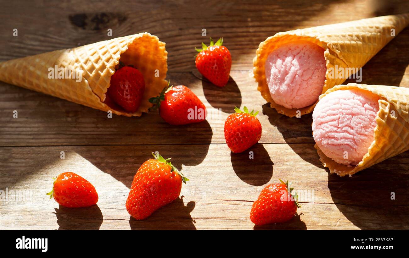 Erdbeereis in einem Waffelkegel. Rote Beeren und Eiskugeln Stockfoto