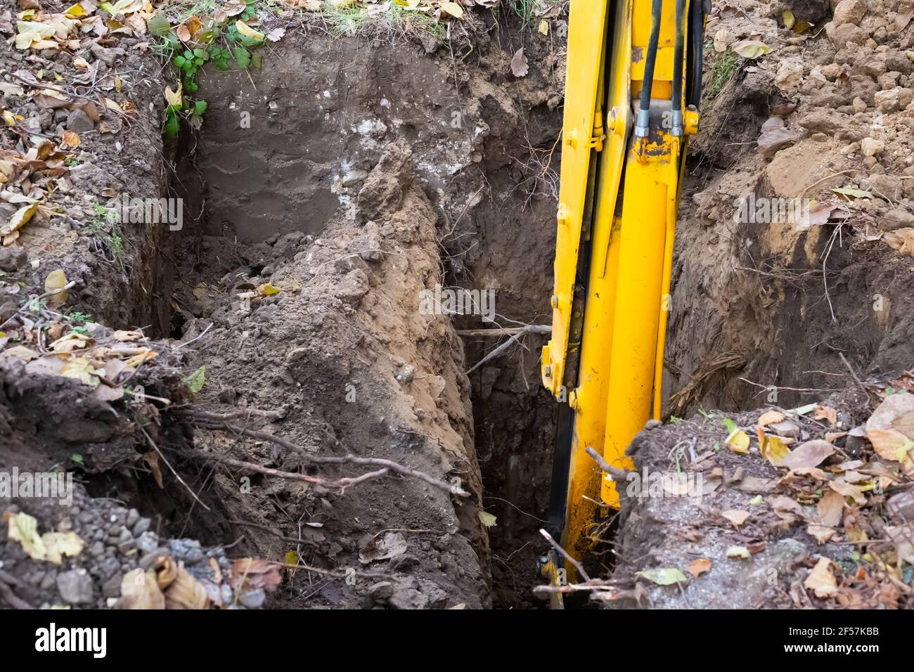 Der Bagger gräbt ein Loch für einen Klärgruben. Arbeiten der Maschine mit dem Boden. Stockfoto