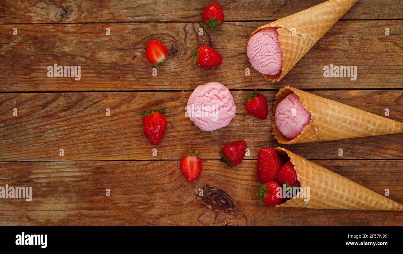 Erdbeereis in einem Waffelkegel. Rote Beeren und Eiskugeln Stockfoto