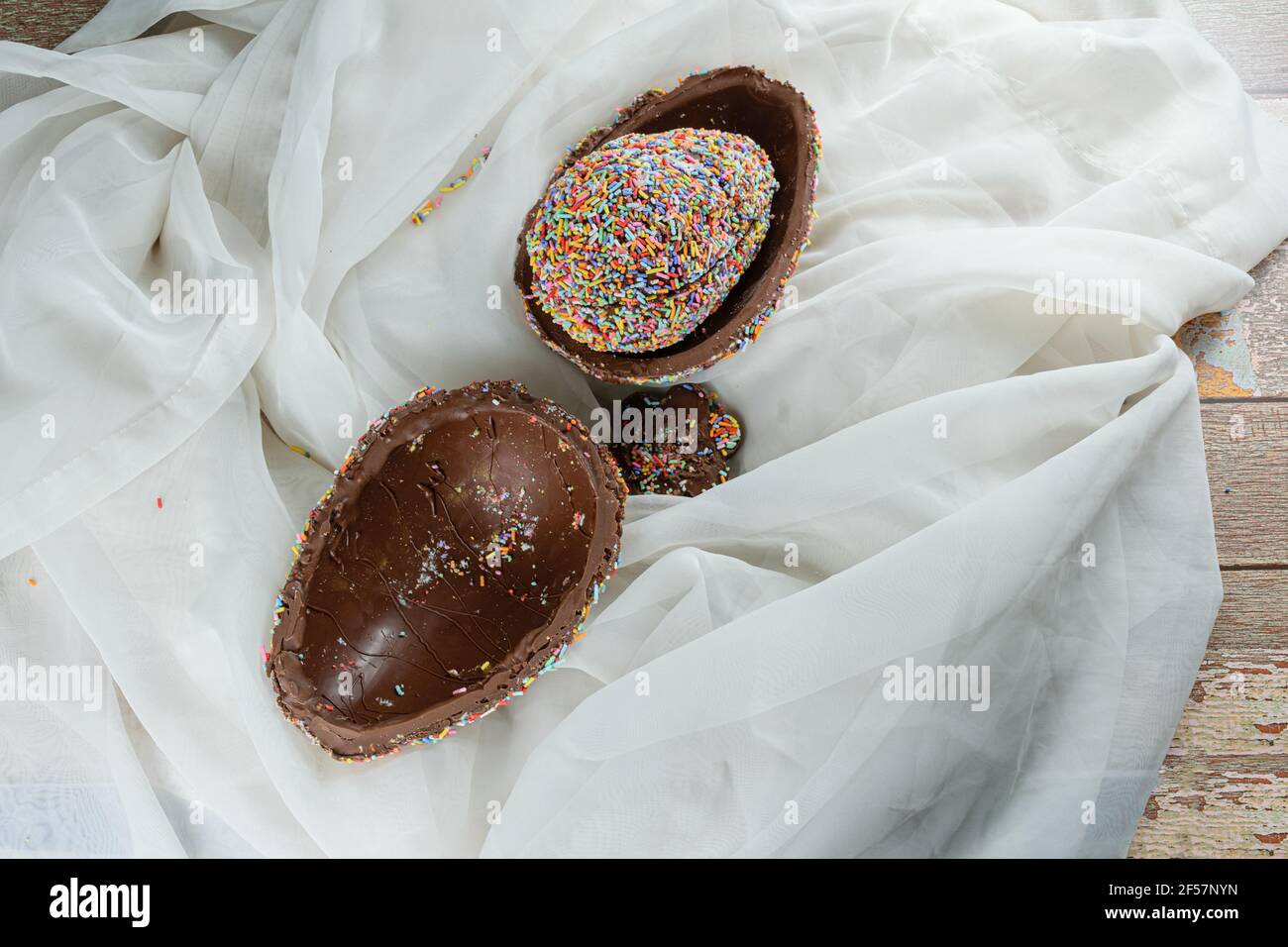 Osterei gefüllt mit einem weiteren Ei mit bunten Schokoladenstreuseln (Pinata Osterei) bedeckt. Stockfoto