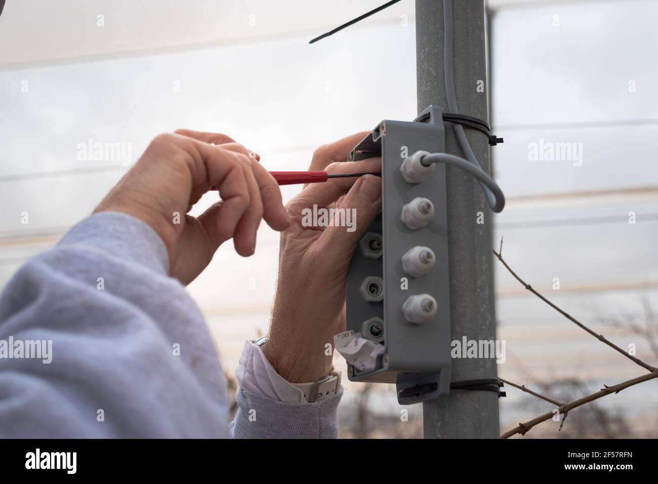 Nahaufnahme der Hände eines kaukasischen Mannes mit einem Schraubendreher bei einer experimentellen Installation im Feld Stockfoto